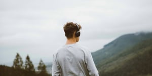 Man with headphones on looking at a landscape.