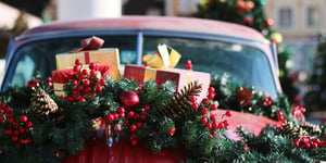 Presents and wreath on top of a vintage red car. 