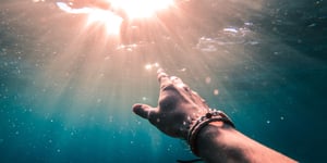 Hand, underwater, reaching towards the light. 