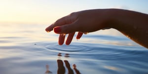 A hand touching the surface of water. 