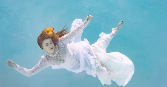 Woman floating under water with her eyes closed.
