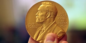  A person holding up a Nobel prize.