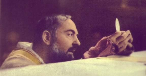 A close up of Padre Pio kneeling at an alter.