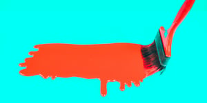 A paint brush dripping orange paint on a turquoise background.