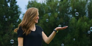 Woman being happy while trying to catch bubbles.