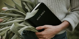 Woman holding palm leaves and the bible.