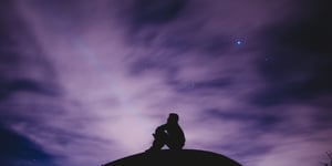 A man looking to the sky that is purple. 