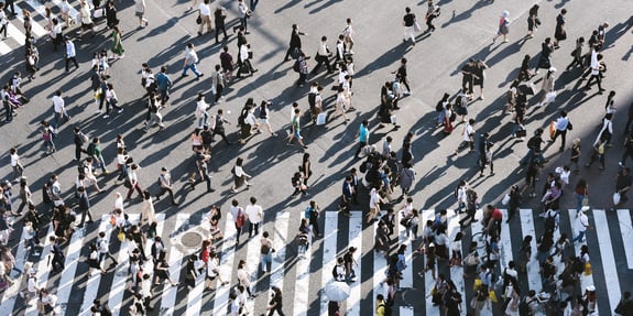 A bunch of people waling on a busy street. 