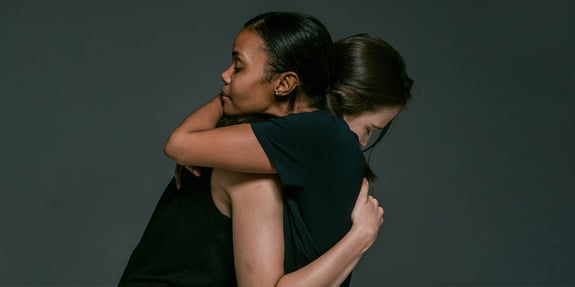 Two women hugging each other with empathy.