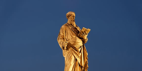 Gold statue of a man with a beard reading a book