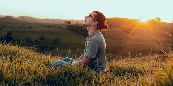 Man sitting peacefully in a field.